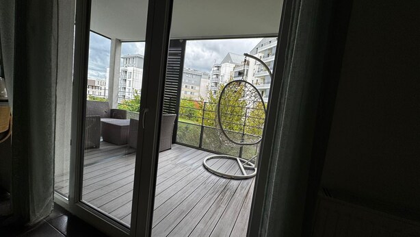 Un balcon donnant sur des immeubles, avec une chaise.