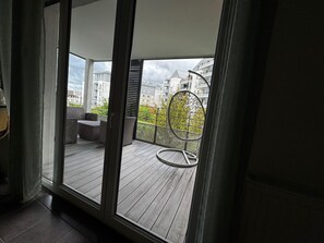 A balcony with a view of buildings and a chair.