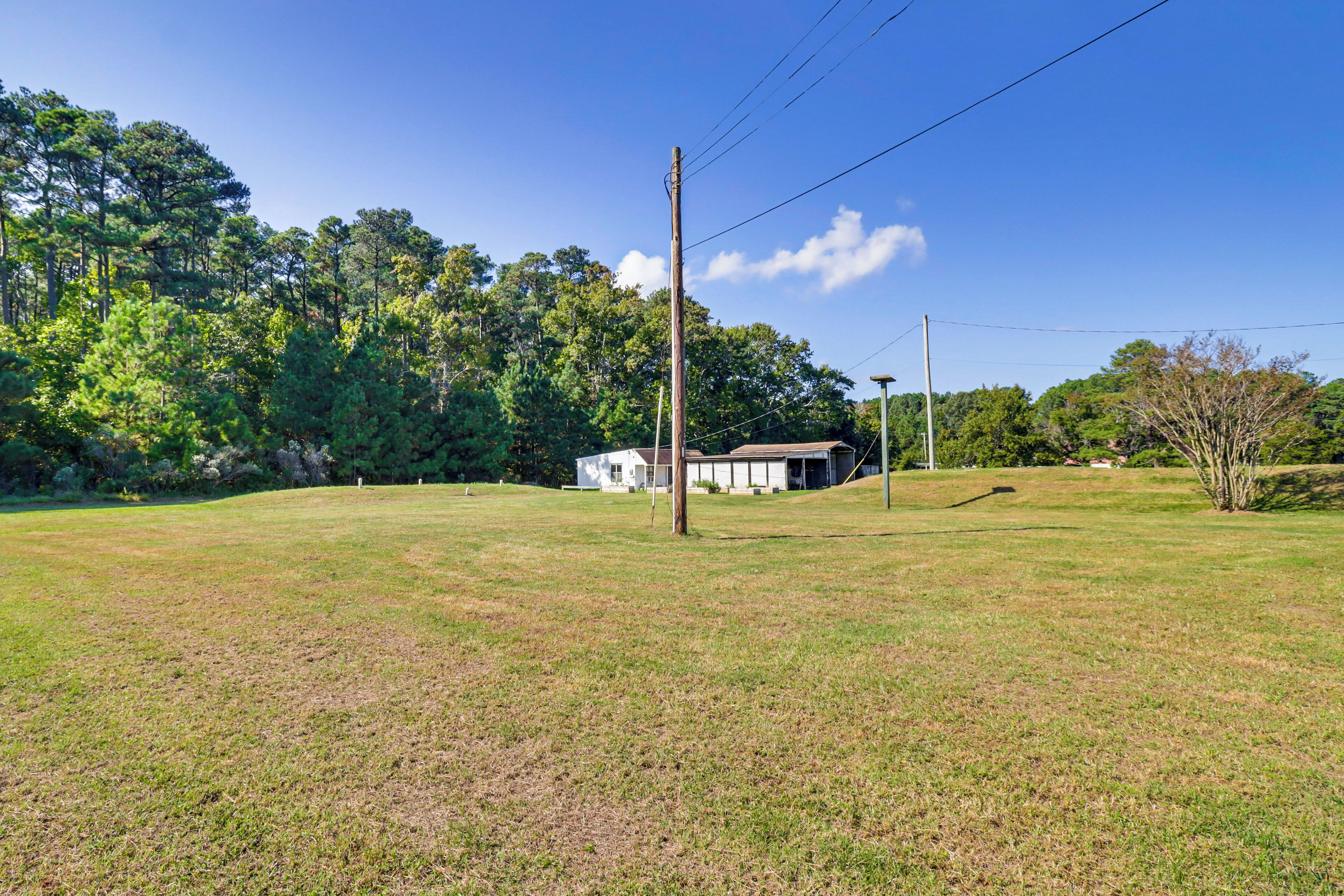 A grassy field with a white building and a utility pole.
