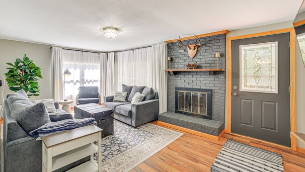 A modern living room with a grey sofa set, a fireplace, and a large window with curtains. - Walk to Water: Lake House in Suring! (Suring)
