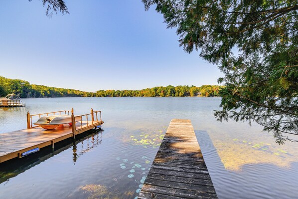 A wooden dock extending into calm water with a boat docked at the end.