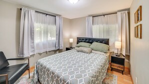 A bedroom with a bed, two bedside tables, a chair, and curtains. - Walk to Water: Lake House in Suring! (Suring)