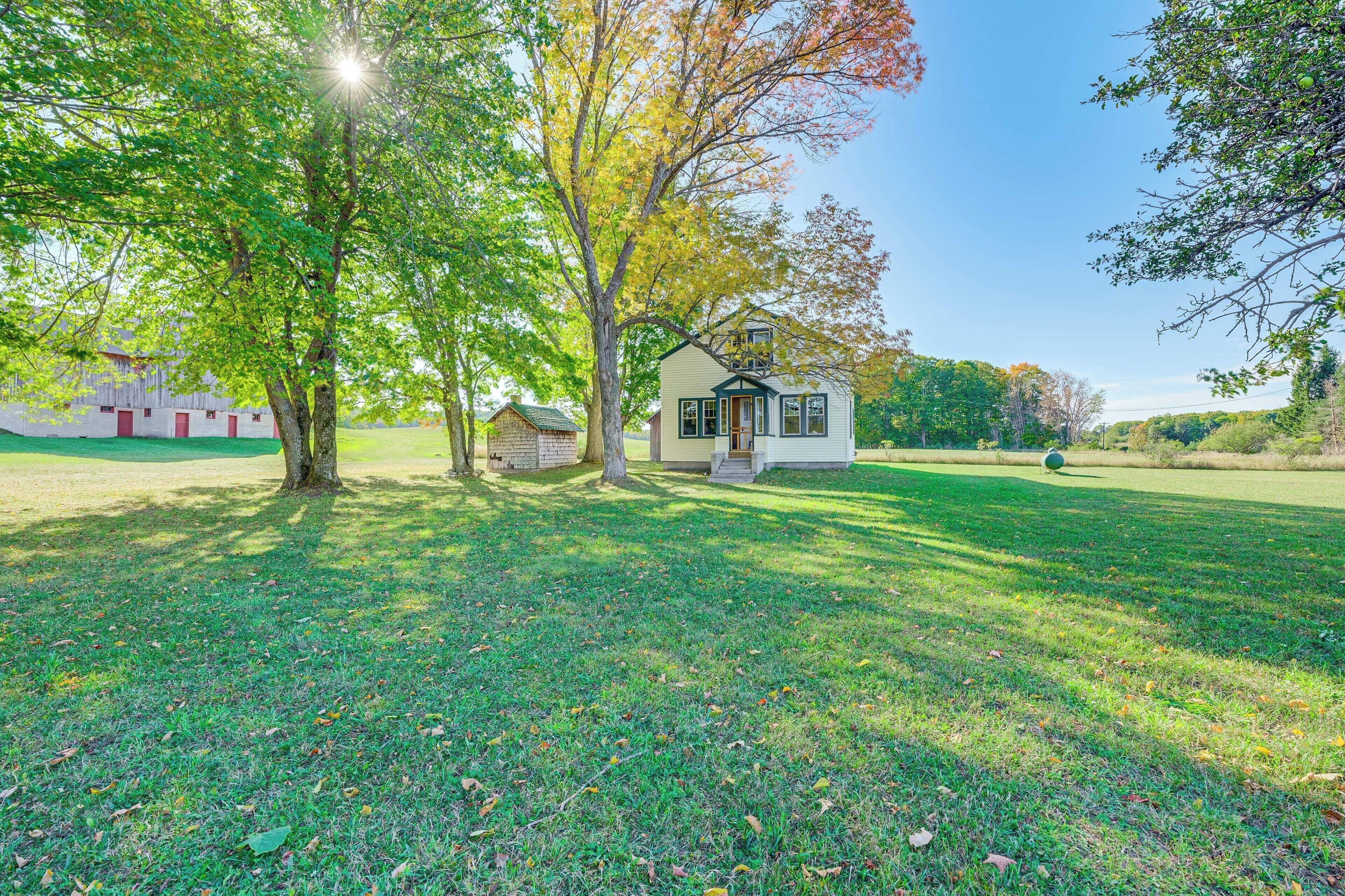A small house with a porch, surrounded by a grassy yard and trees.