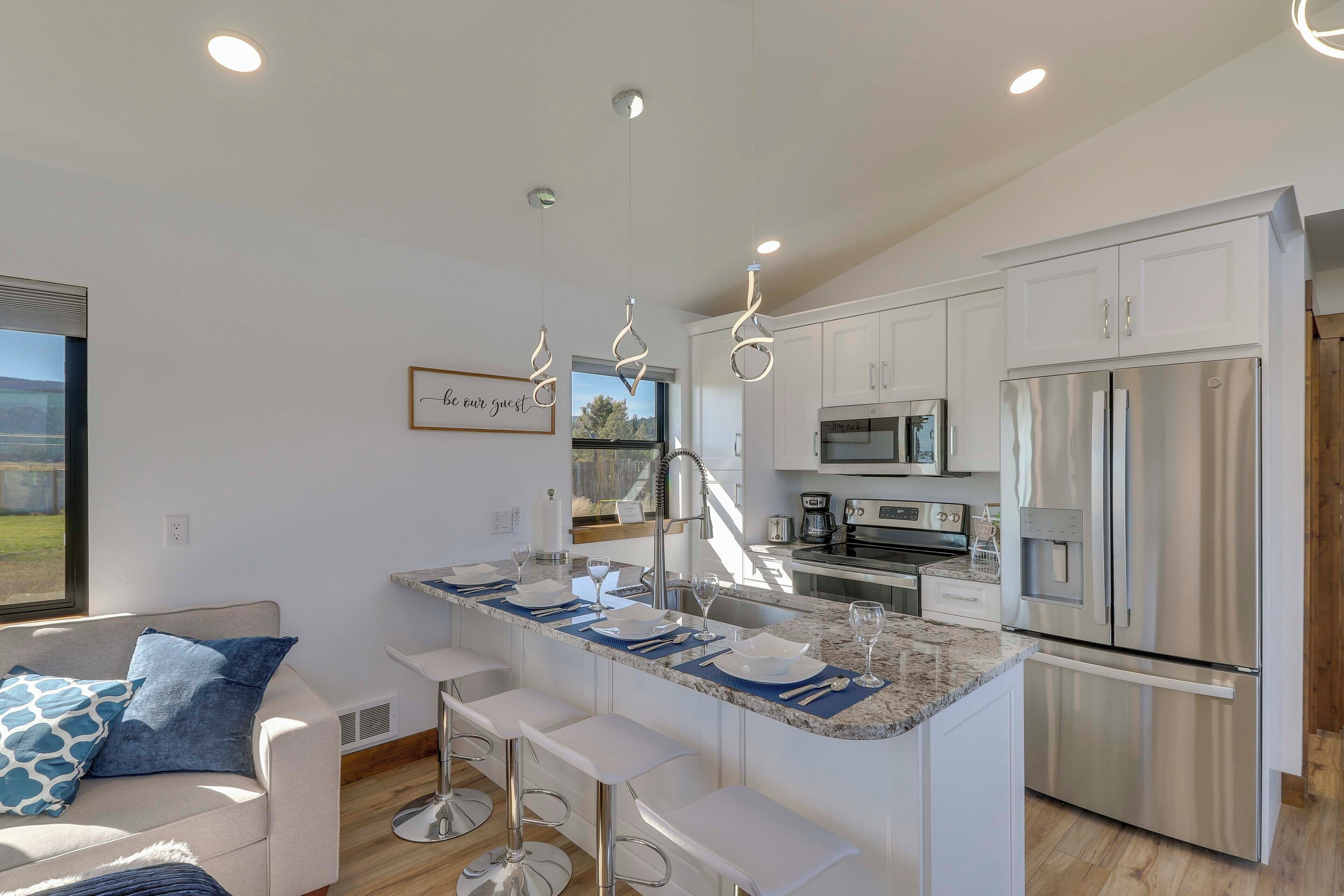 A modern kitchen with white cabinetry, stainless steel appliances, and a central island with bar stools.