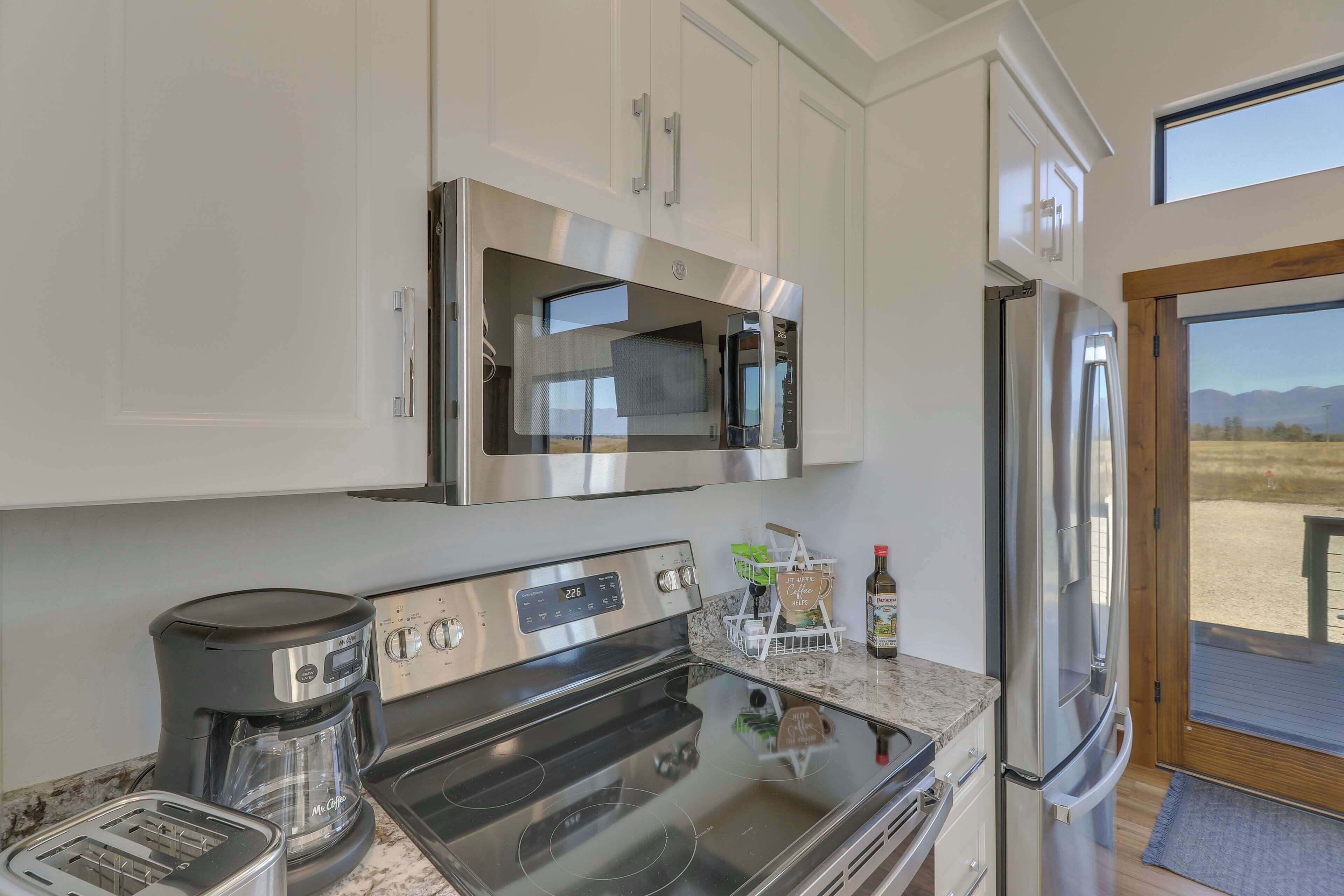 A modern kitchen with stainless steel appliances, a coffee maker, and a view of the outdoors.