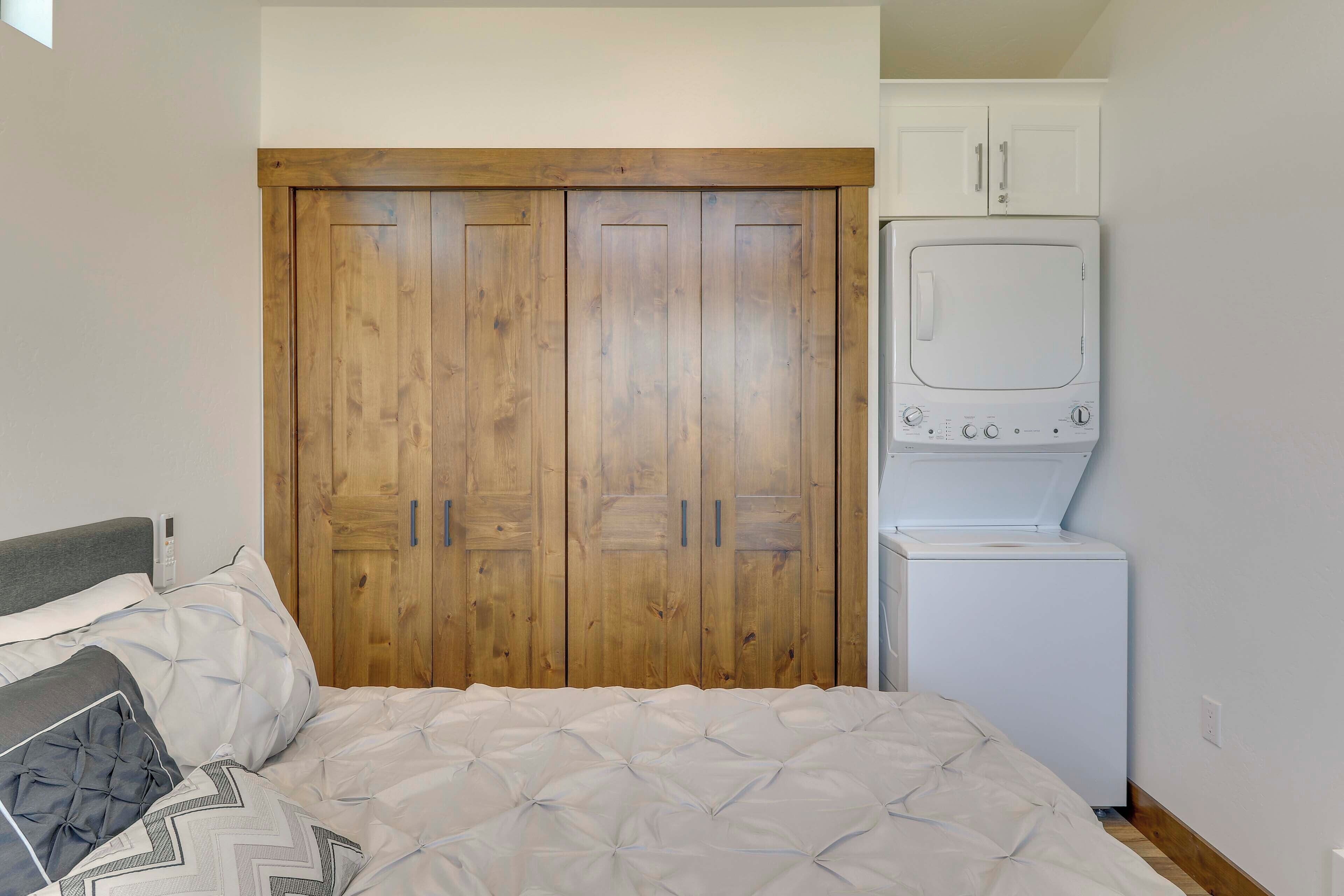 Un dormitorio con un armario de madera, lavadora y una cama con ropa de cama estampada.