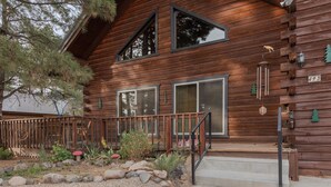 A wooden cabin with a stone pathway, wooden deck, and a small porch. - Cozy Cabin | New Hot Tub! Near Shopping, Dining, Skiing, Golfing (Pagosa Springs)