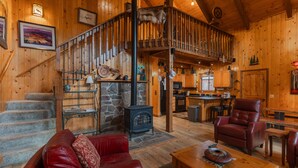 A wooden interior with a staircase, a fireplace, a red leather sofa, and a dining area. - Cozy Cabin | New Hot Tub! Near Shopping, Dining, Skiing, Golfing (Pagosa Springs)