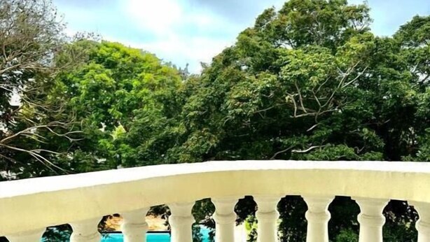 A white balustrade with a view of a swimming pool and lush greenery. - Lux Suites Kwamby Ocean paradise (Mombasa)