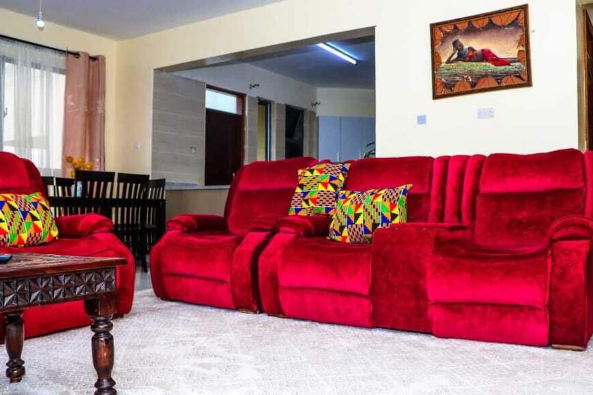A living room with a red sofa set, a wooden coffee table, and a painting on the wall.