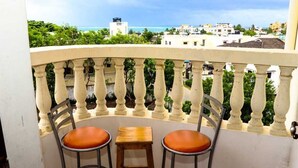 A balcony with two chairs and a small table, overlooking a coastal area with buildings and greenery. - Lux Suites Kwamby Ocean paradise (Mombasa)