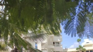 A building with a courtyard, palm trees, and a clear sky. - Lux Suites Kwamby Ocean paradise (Mombasa)