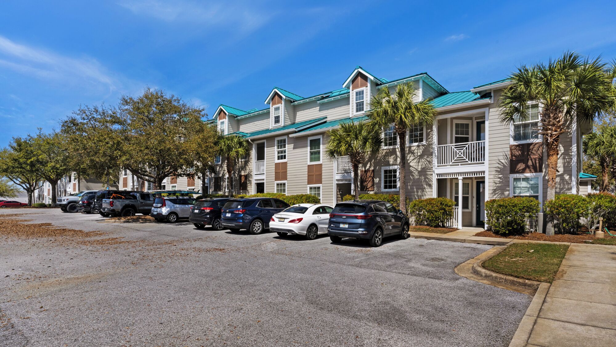 A multi-story residential building with a parking lot in front.