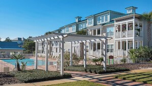 A two-story building with a covered outdoor seating area and a swimming pool. - Modern 2BR/2BA Condo Near Beach + Free Attraction Tickets! (Santa Rosa Beach)