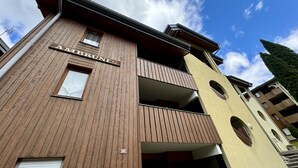Een meerlaags gebouw met een houten gevel, balkons en een bord met de tekst 'AMBRUNES'.