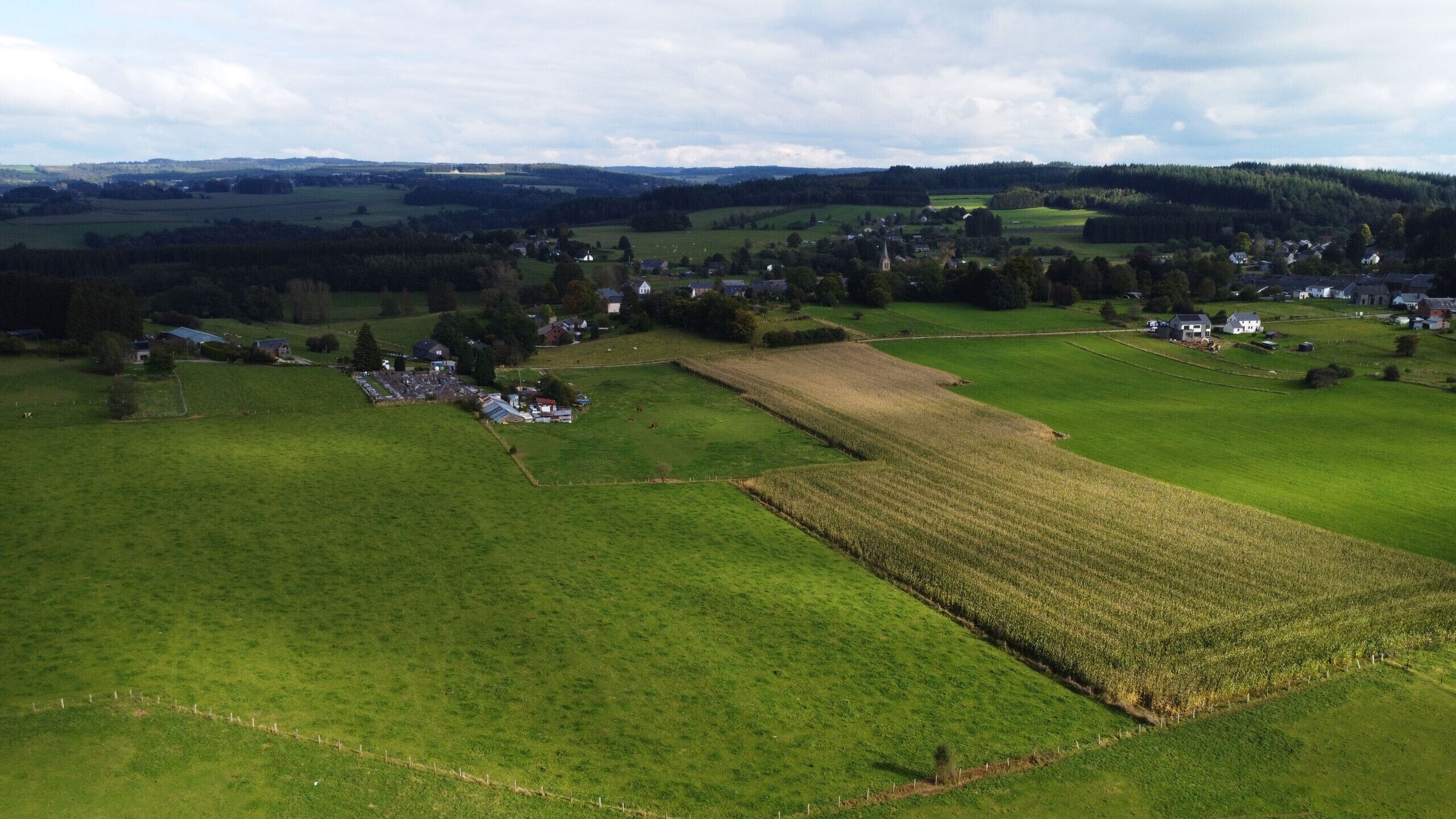 An aerial view of a rural landscape with fields, a small village, and a church.