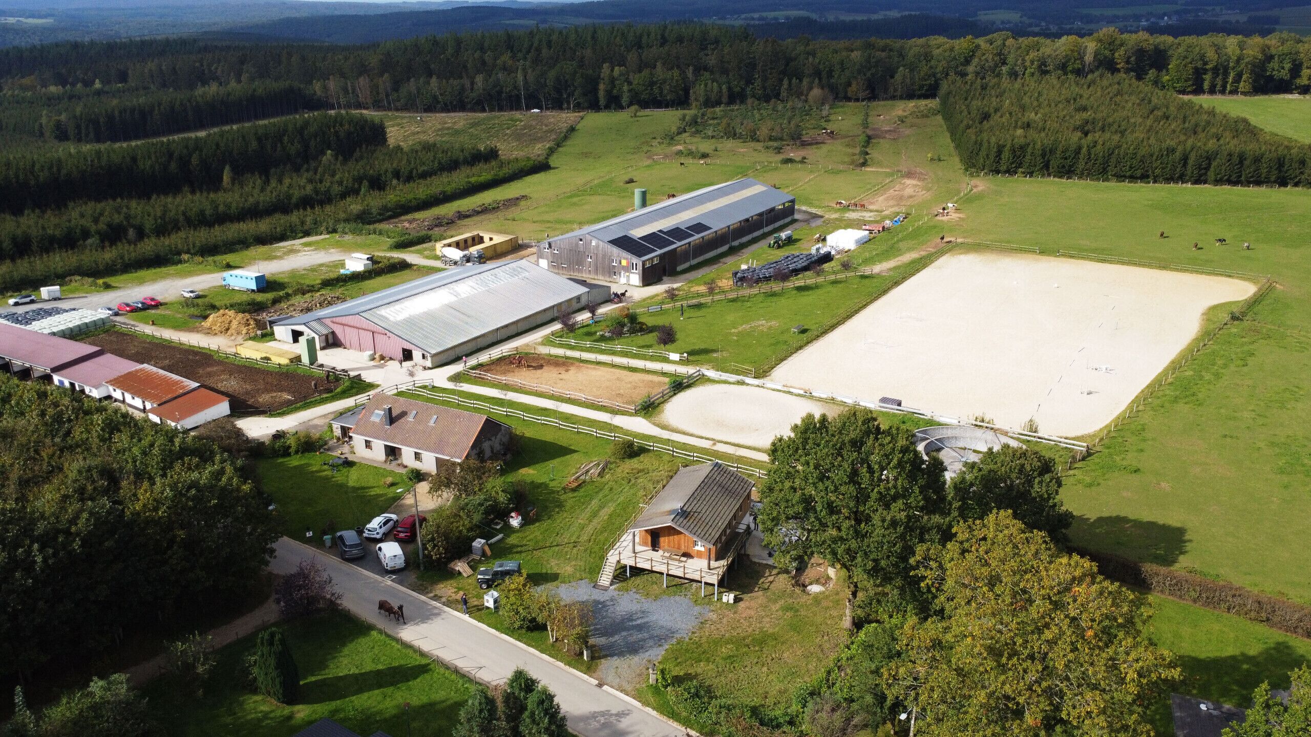 An aerial view of a large farm with multiple buildings, including a barn, a stable, and a large open field.