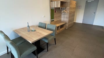 A room with a wooden table and four chairs, a bench, a coat rack, and a door.