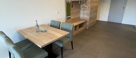 A room with a wooden table and four chairs, a bench, a coat rack, and a door.