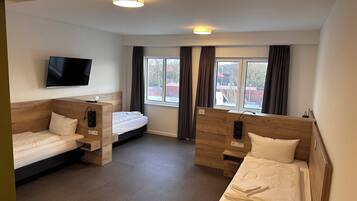 Eenvoudige vierpersoonskamer | Een bureau, een laptopwerkplek, verduisterende gordijnen