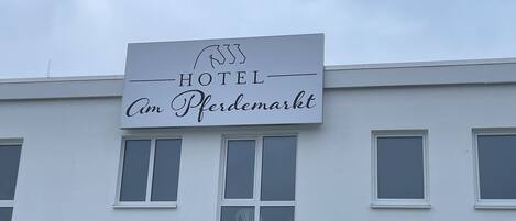 A hotel sign with the name "HOTEL Am Pferdemarkt" and a "CHECK-IN" sign below it.