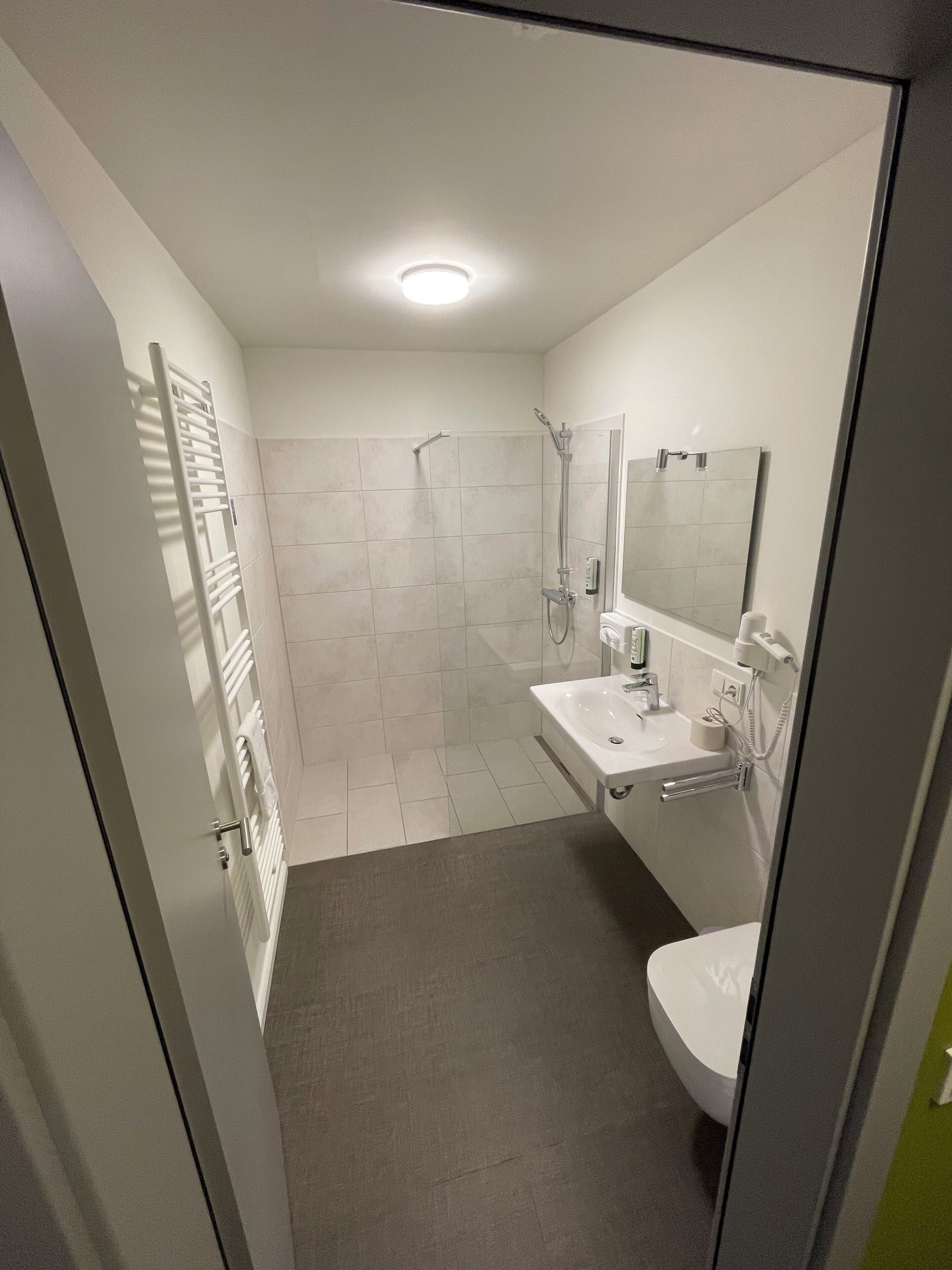 A modern bathroom with a shower, a sink, and a toilet.