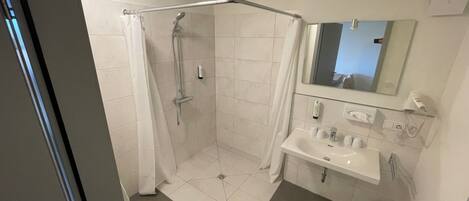 A modern bathroom with a shower, toilet, and sink.