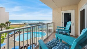Ein Balkon mit Pool, Stühlen und Blick aufs Meer.