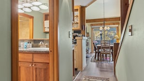 A wooden interior hallway leading to a dining area with a chandelier, wooden cabinets, and a view of the outdoors. - Outpost: Columbine 1024 - Aspens Location! (Wilson)