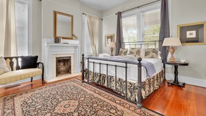 Un dormitorio con cama con dosel, chimenea, banco y alfombra grande.