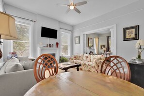 Un salon comprenant un canapé, des fauteuils, une table, un ventilateur de plafond, un téléviseur et une cheminée.