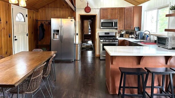 A spacious kitchen with wooden cabinets, stainless steel appliances, and a large island with stools.