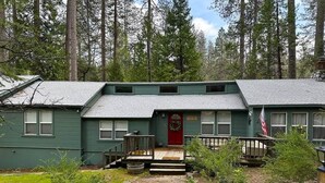 A two-story house with a stone pathway leading to the front door, surrounded by a forest.