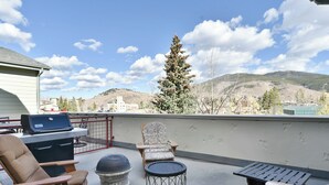 A rooftop patio with outdoor furniture, a grill, and a view of a mountain. - La Riva Del Lago Condo: Downtown, Close to Everything! (Dillon)