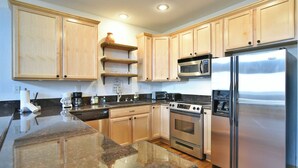 A modern kitchen with wooden cabinets, stainless steel appliances, granite countertops, and a built-in oven. - La Riva Del Lago Condo: Downtown, Close to Everything! (Dillon)