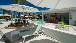 Ett område vid poolen med solstolar, parasoller och en restaurang.