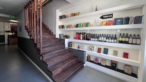 A staircase with wooden steps leading to a white wall with shelves containing books and wine bottles. - Meidan Inn (Tbilisi)