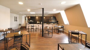 A modern kitchen with a central island, wooden flooring, and a dining area with tables and chairs. - Meidan Inn (Tbilisi)