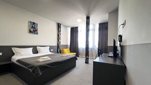 A hotel room with a bed, a desk, and a chair. - Meidan Inn (Tbilisi)