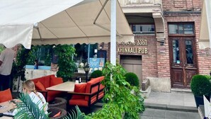 A building with a sign for 'MEIDAN INN' and 'KHINKALI PUB' with outdoor seating and a covered area. - Meidan Inn (Tbilisi)