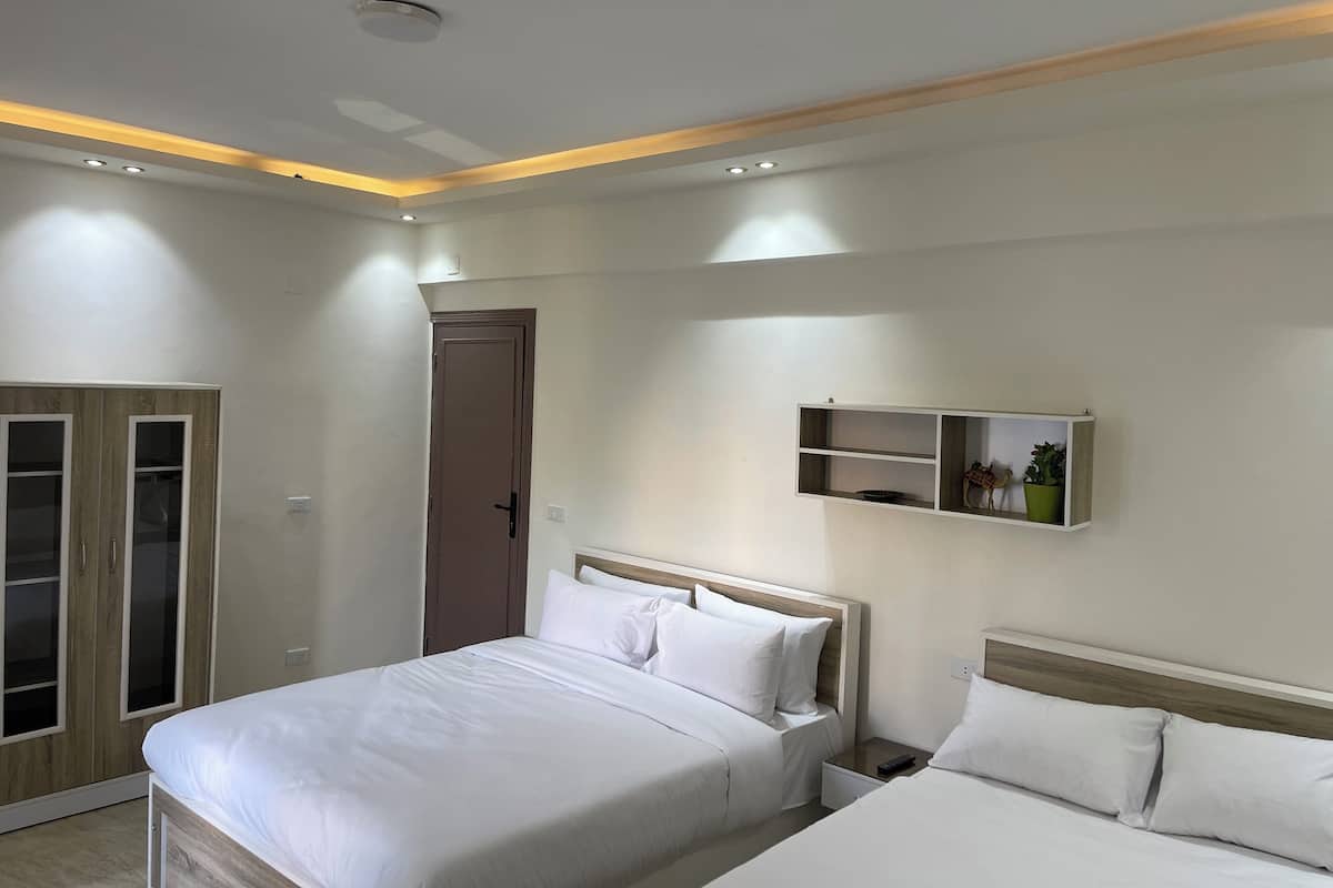 Un dormitorio moderno con cama, mesitas de noche, un armario y una estantería con adornos.