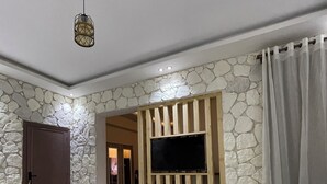 Camera d'albergo con due letti, televisore montato su un pannello di legno, decorazioni a parete in pietra e pavimento in pietra.