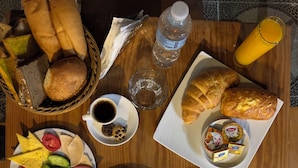 Una tavola imbandita per la colazione con pane, pasticcini, frutta, un fornello e condimenti.