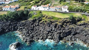 An aerial view of a coastal village with houses built on a hillside overlooking the ocean. - St. John's House (São João)
