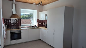 A modern kitchen with white cabinets, a stainless steel range hood, a window with a view, and a tiled floor. - St. John's House (São João)