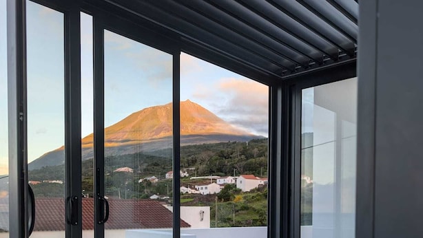 A balcony with a glass table and wicker furniture, overlooking a mountainous landscape. - St. John's House (São João)