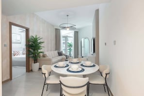 A modern dining area with a round table, white chairs, and a potted plant.