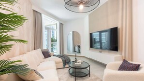 Un salon moderne comprenant un canapé, des fauteuils, une table basse, un téléviseur et un grand miroir.