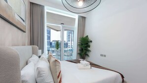 Une chambre d’hôtel moderne dotée d’un grand lit, offrant une vue sur la ville et comprenant un balcon avec une chaise et une plante.