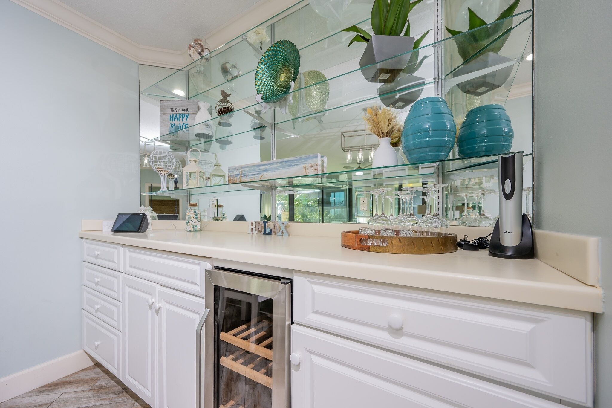 A kitchen with a glass display case, white cabinetry, and a built-in wine cooler.